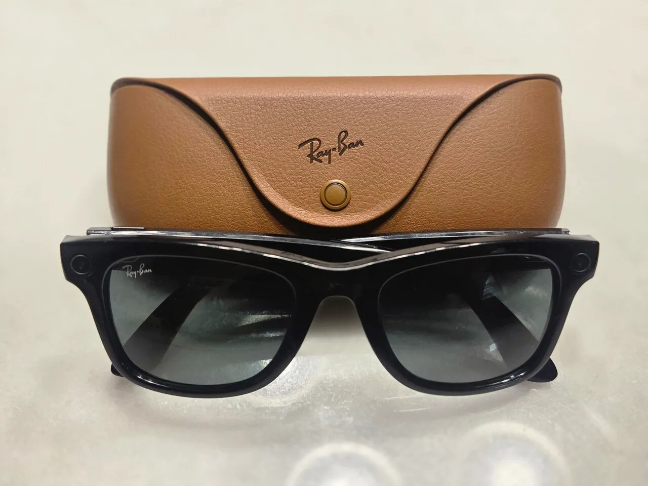 Een Ray-Ban Meta-slimme bril met camera, staand voor het leren oplaadetui.